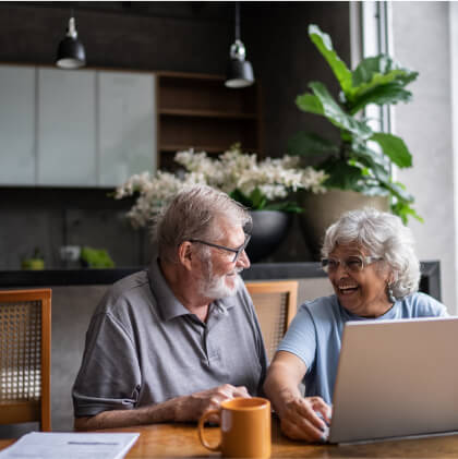 mature couple smiling in front of laptop