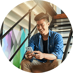 Young man sitting on staircase using smartphone