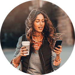 Woman walking with coffee cup in one hand and cell phone in the other