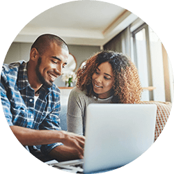 Couple sitting on couch together looking at laptop together