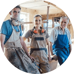 two men and a woman dressed for working in a carpentry shop smile for the camera